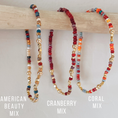 Load image into Gallery viewer, Three beaded necklaces labeled 'American Beauty Mix', 'Cranberry Mix', and 'Coral Mix' on a wooden stick.
