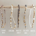 Load image into Gallery viewer, Set of beaded bracelets in various colors hanging on a stick with labels below.