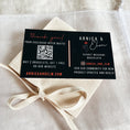 Load image into Gallery viewer, Black business card with white text and QR code on a beige fabric background