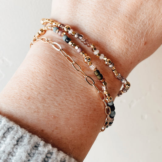 Close-up of a wrist wearing multiple bracelets on a neutral background